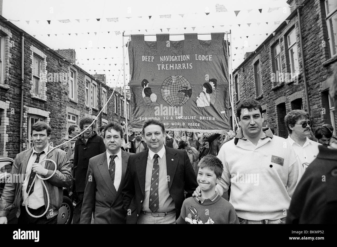 Minatori del carbone e famiglie marzo attraverso il villaggio su ultimo giorno di lavoro alla navigazione profonda Colliery Treharris Glamorgan Galles del Sud Foto Stock