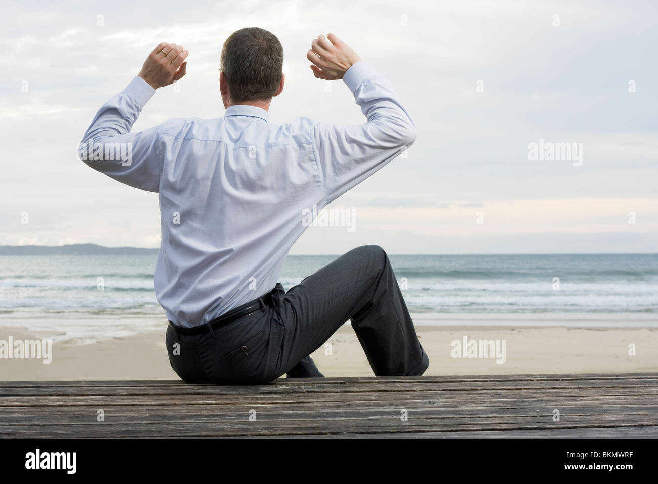 Imprenditore rilassante al mare seduti su una piattaforma di legno Foto Stock