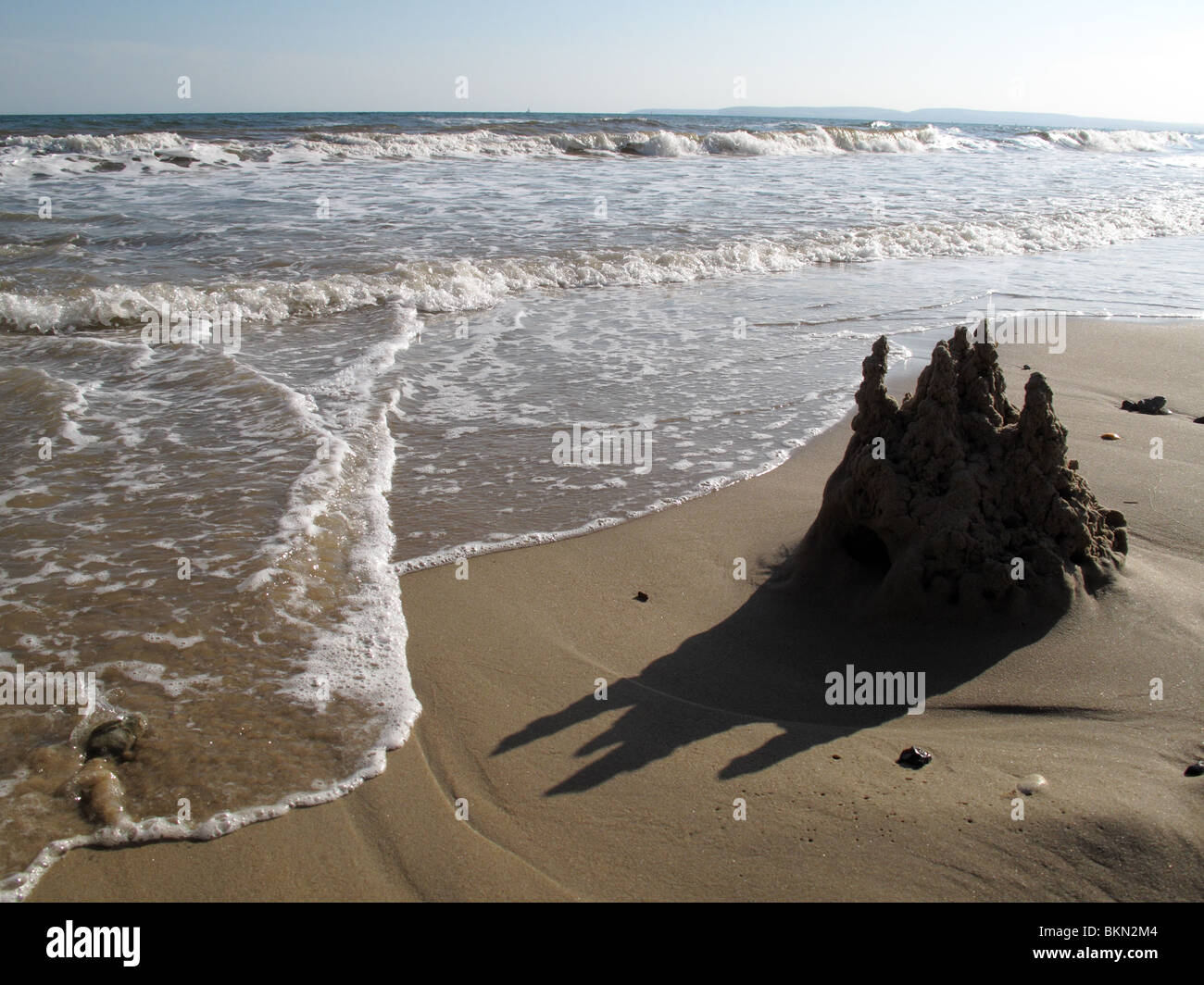 Castello di sabbia lavando via Foto Stock