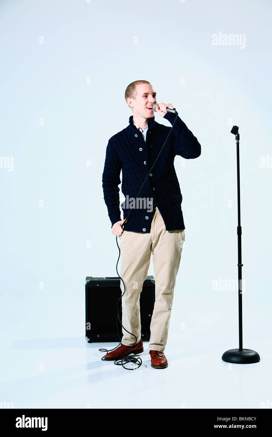 Un giovane uomo cantano in un microfono Foto Stock