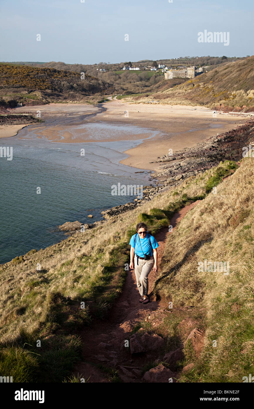 Femmina su a piedi Il Pembrokeshire Coast path a Manorbier con la spiaggia e il castello di sfondo Wales UK Foto Stock