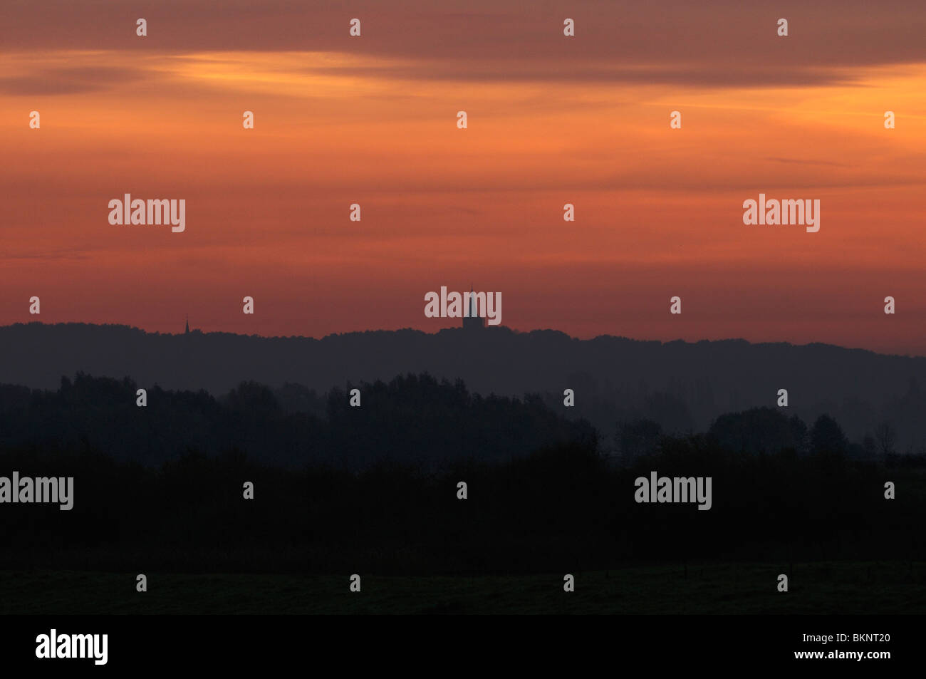 Kerktoren piekend boven lagenspel bij zonsopgang; Chiesa fuoruscita di diversi strati durante il sunrise Foto Stock