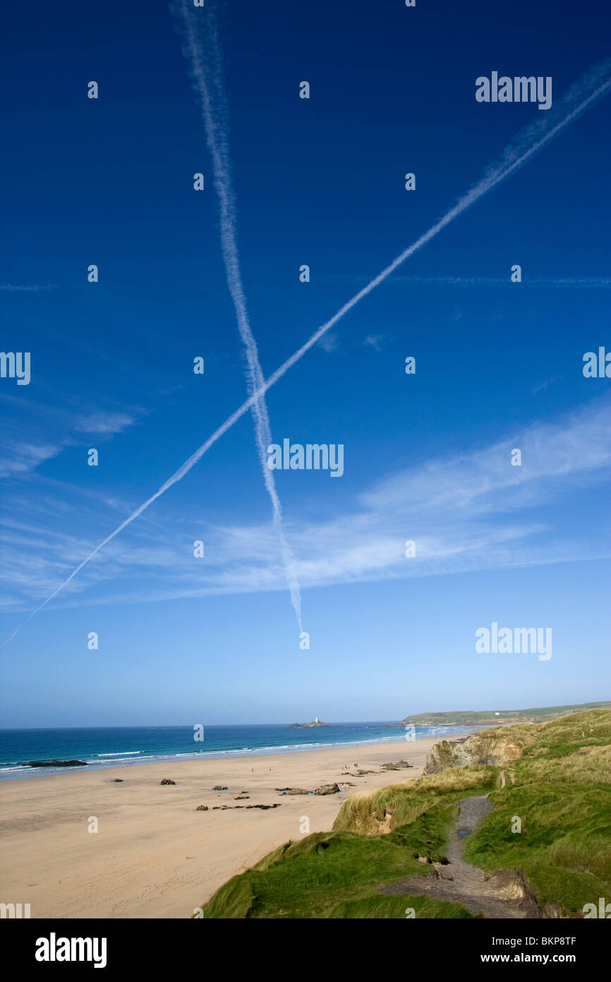 Sentieri a getto da compagnie aeree internazionali croce nel cielo sopra la spiaggia di Godrevy, Penwith, Cornwall Regno Unito Foto Stock