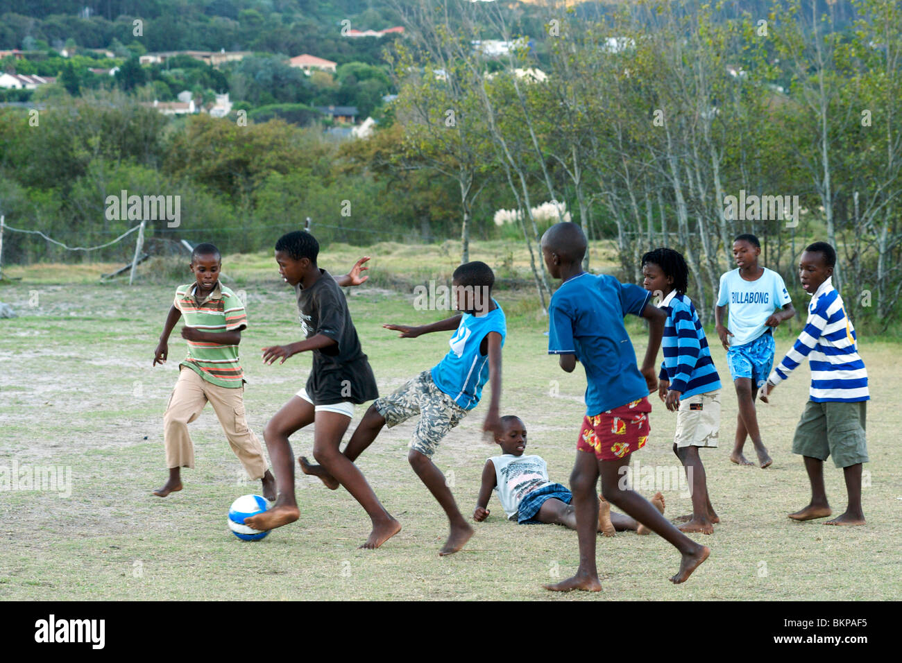 I bambini africani che giocano a calcio a piedi nudi in un campo di Hout Bay a Cape Town, Sud Africa. Foto Stock
