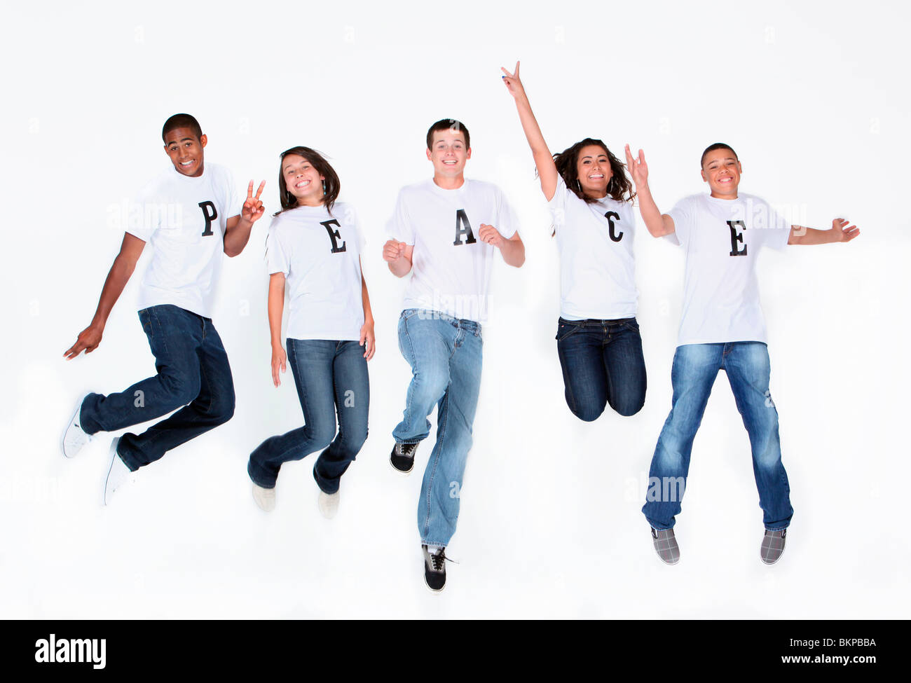 Un gruppo di adolescenti di saltare in aria con le loro T-Shirt ortografia 'pace' Foto Stock