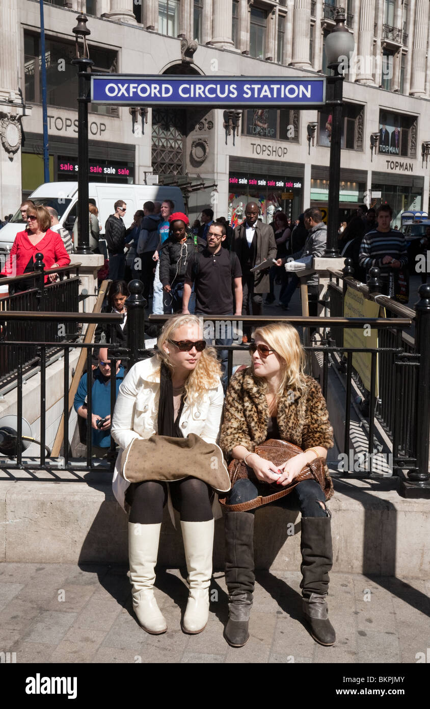 Due ragazze seduta a Oxford Circus, ingresso alla stazione della metropolitana,London REGNO UNITO Foto Stock