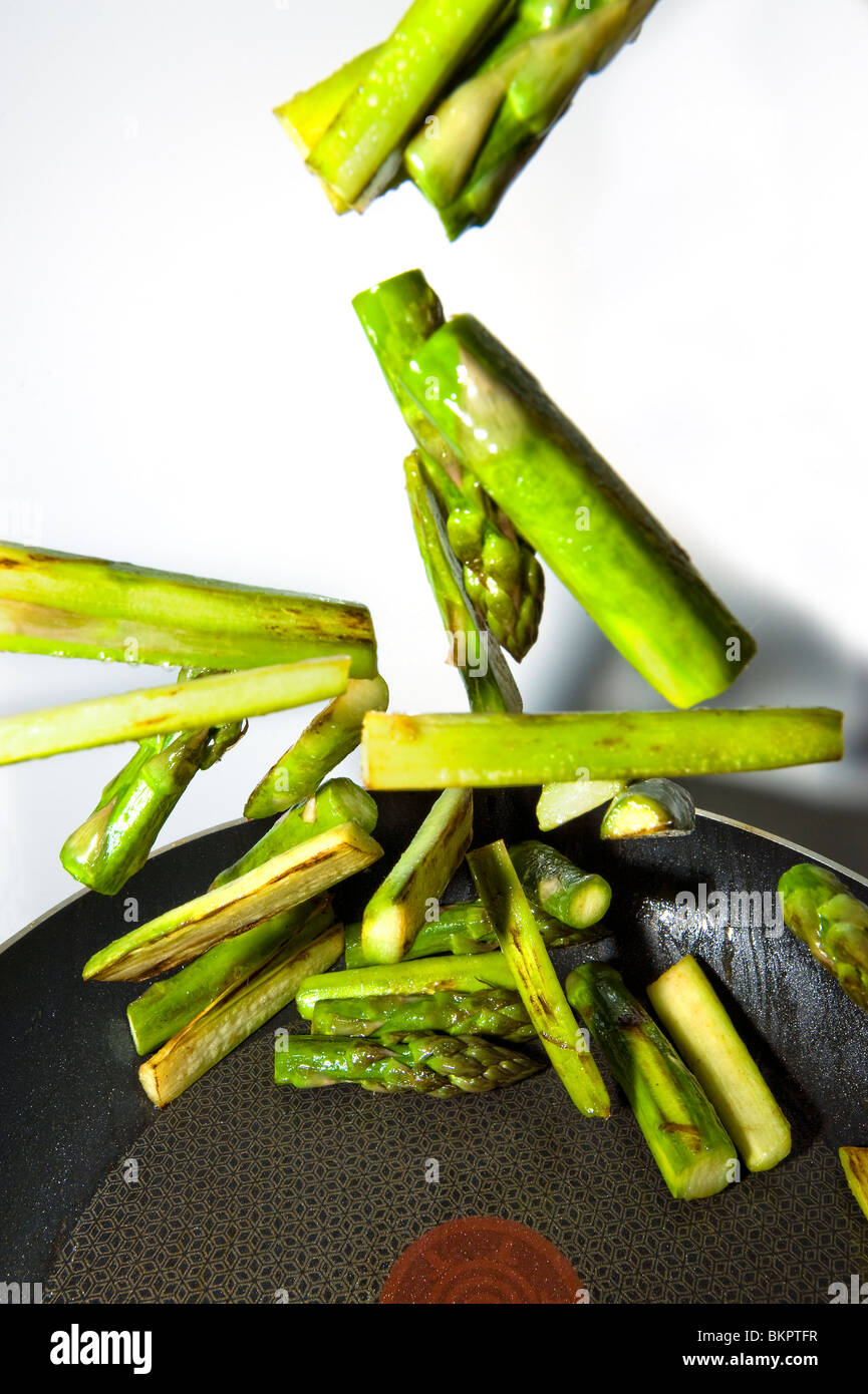 Arrosto di fry tostatura di friggere gli asparagi verdi vegetale in una padella casseruola spargel wok asparagi freschi ortaggi organtic sani Foto Stock
