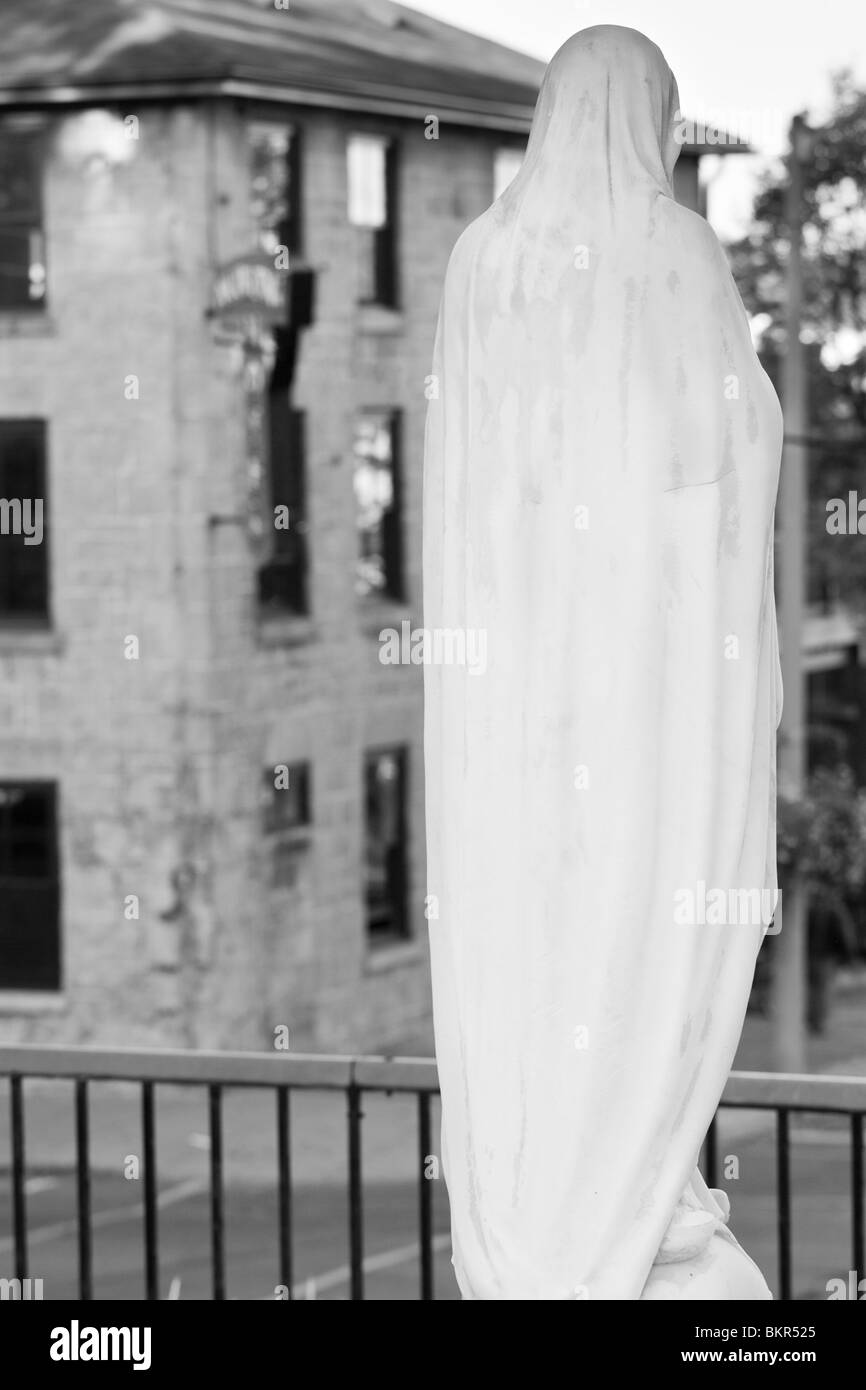 Il retro di una statua bianca di una figura religiosa, cerca su una strada principale di seguito. Foto Stock