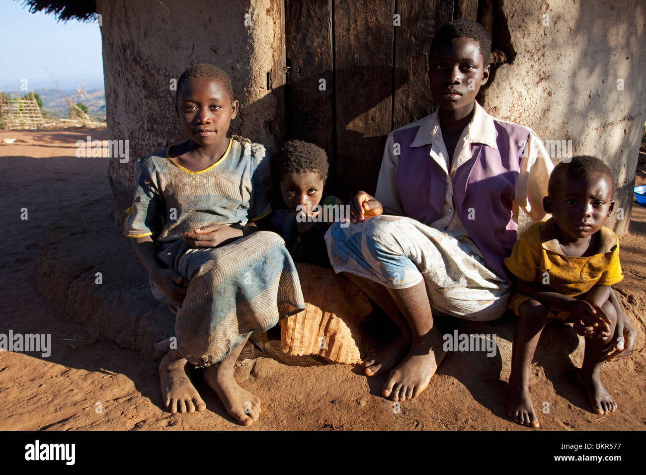 Il Malawi, Lilongwe, Ntchisi Riserva Forestale. Una giovane famiglia siede dall ingresso al loro rifugio in un paese di montagna. Foto Stock