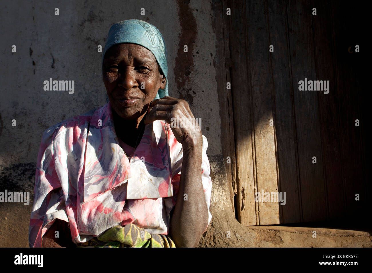 Il Malawi, Lilongwe, Ntchisi Riserva Forestale. Una vecchia donna si siede con entrata al suo rifugio in un paese di montagna. Foto Stock