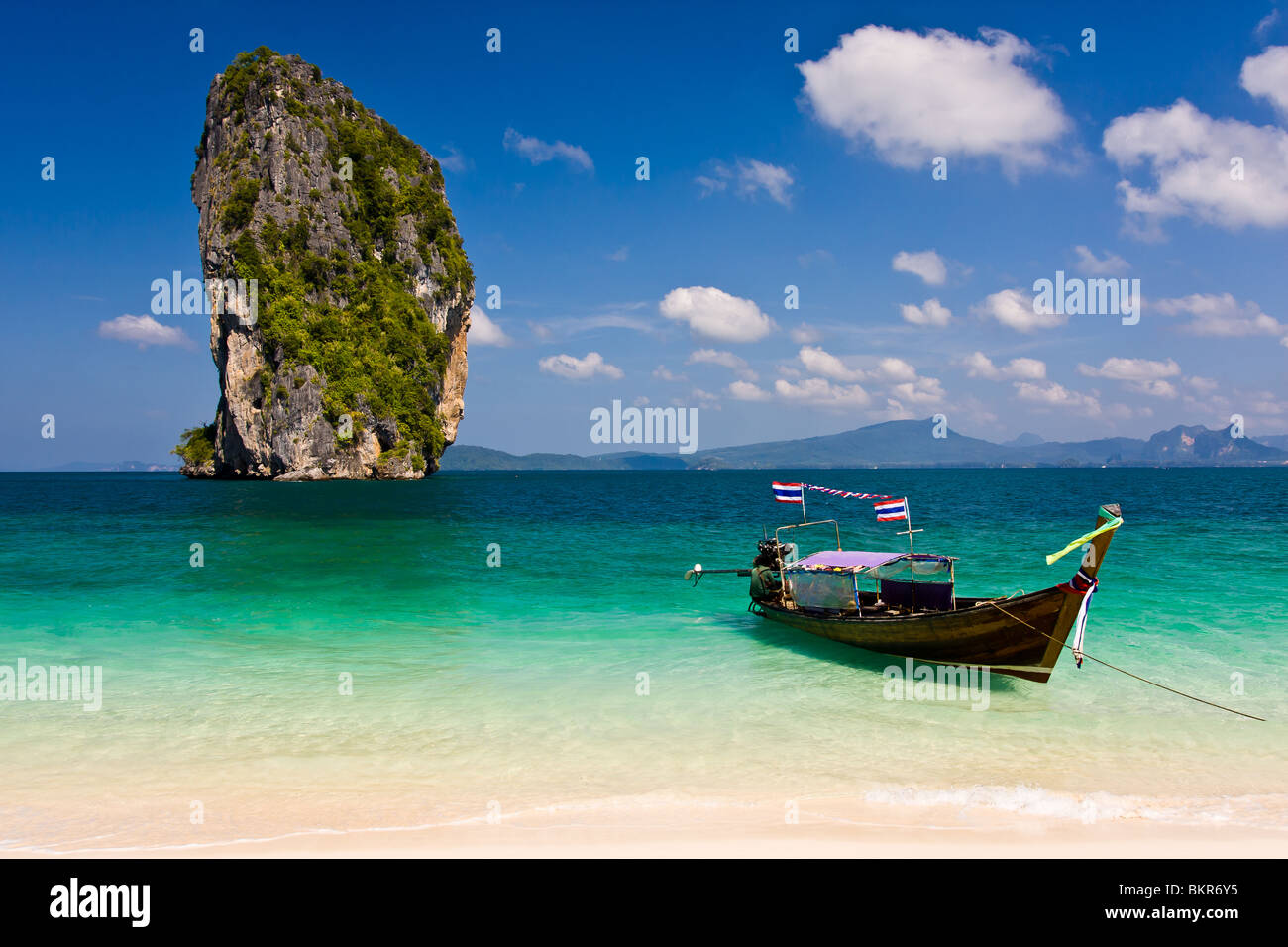 Barca dalla coda lunga parcheggiato su una spiaggia di Isola tropicale con stone island su un orizzonte Foto Stock