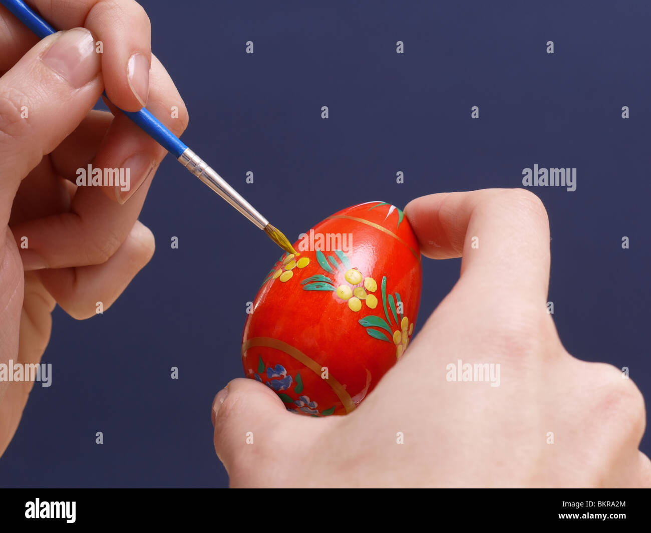 Femmina dipinto a mano uovo di pasqua picchiettio floreale con pennello Foto Stock
