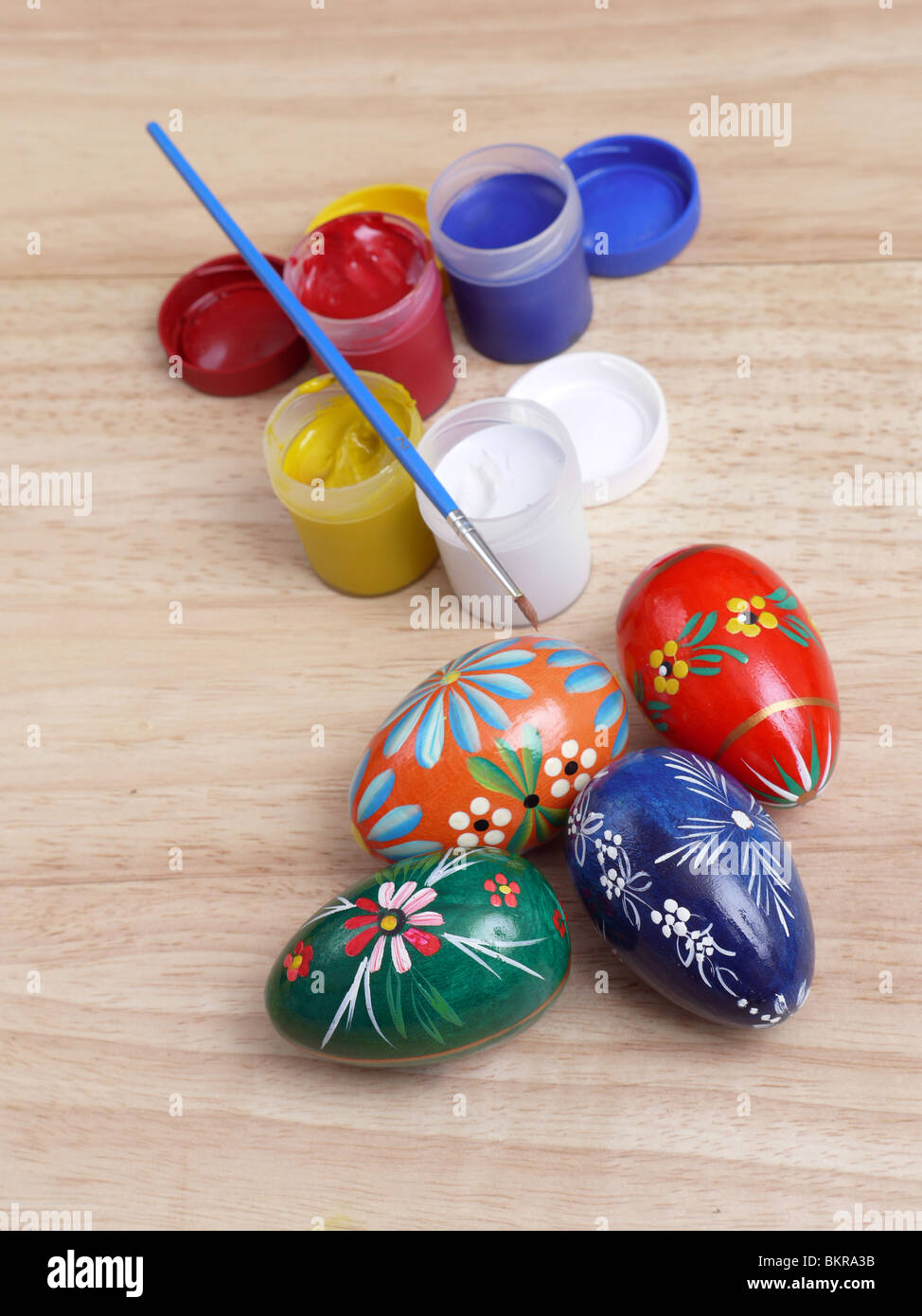 Le uova di pasqua, tubi di vernice e il pennello sul tavolo di legno Foto Stock