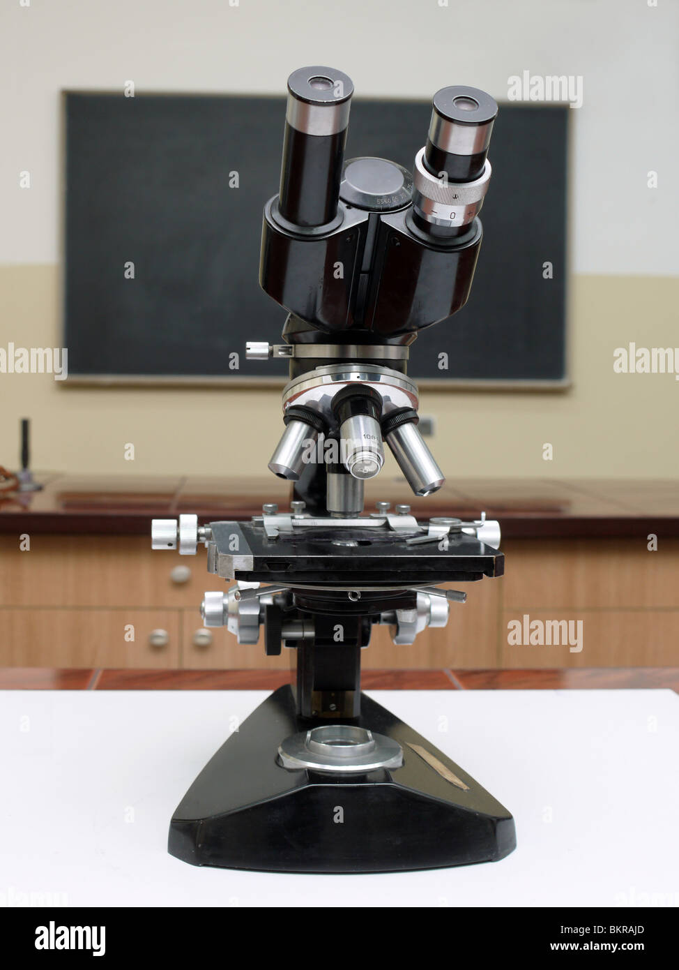 Vecchia scuola di microscopio in aula con la lavagna in background Foto Stock