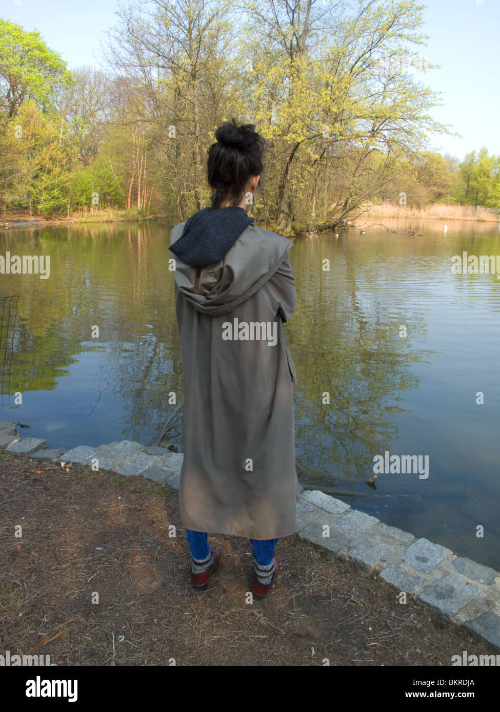 Giovane donna medita le cose oltre il lago in Prospect Park Brooklyn New York. Foto Stock