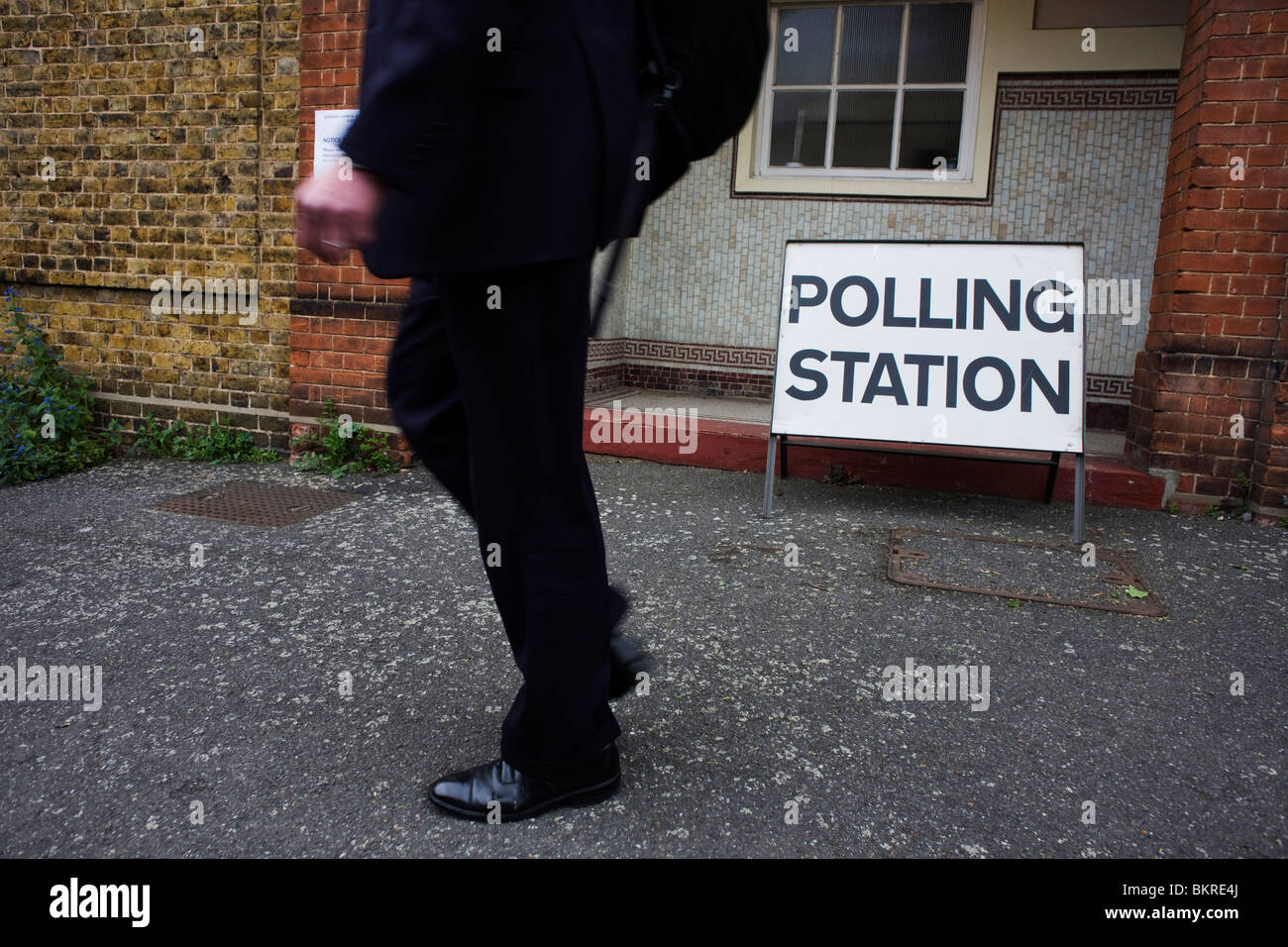Un imprenditore/passeggiate di " commuters " passato la locale stazione di polling il giorno delle elezioni Foto Stock