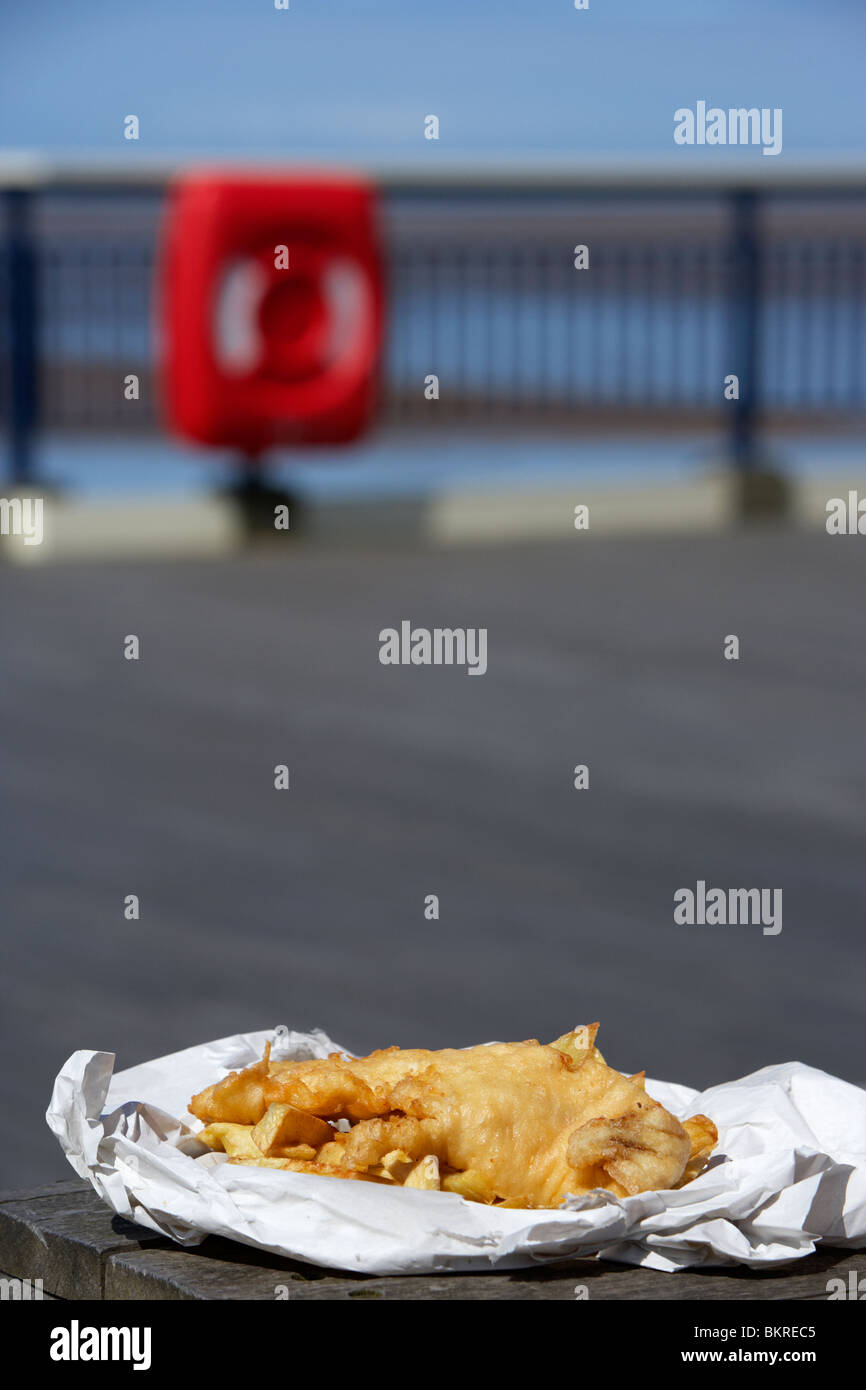 Inglese tradizionale con pesce e patatine in involucro di carta su un molo sul mare Inghilterra Regno Unito Foto Stock Inglese tradizionale con pesce e patatine in involucro di carta su un molo sul mare Inghilterra Regno Unito Foto Stock