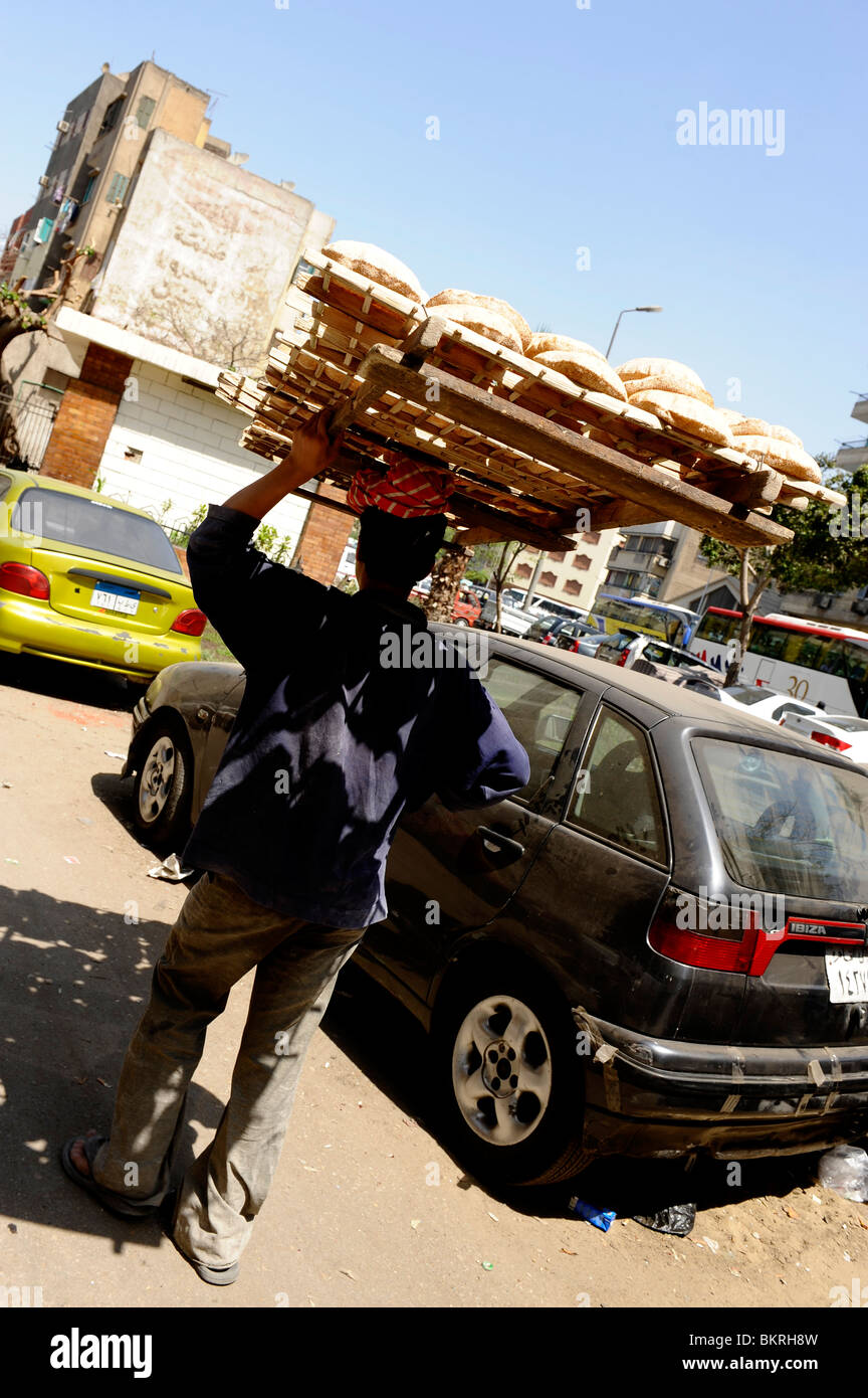 Pane ragazzo delle consegne con cestino del pane del nesting sulla sua testa , strade del Cairo , Egitto Foto Stock