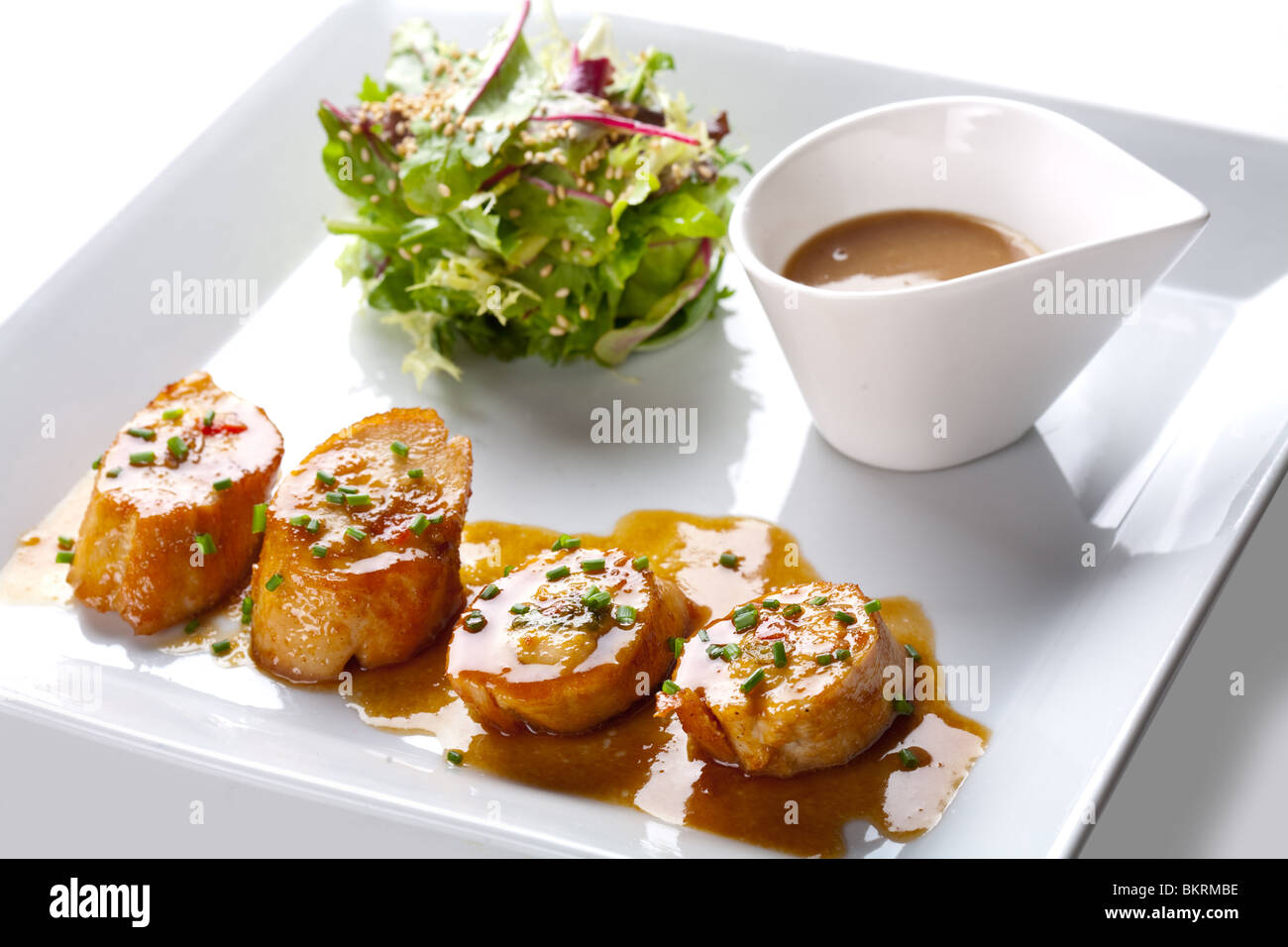 Capesante con insalata e salsa su piastra bianca Foto Stock