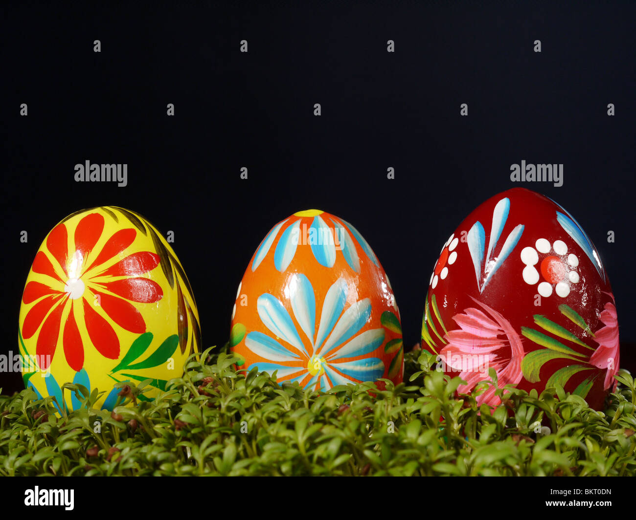 Tre dipinti di uova di pasqua in cress su sfondo nero Foto Stock