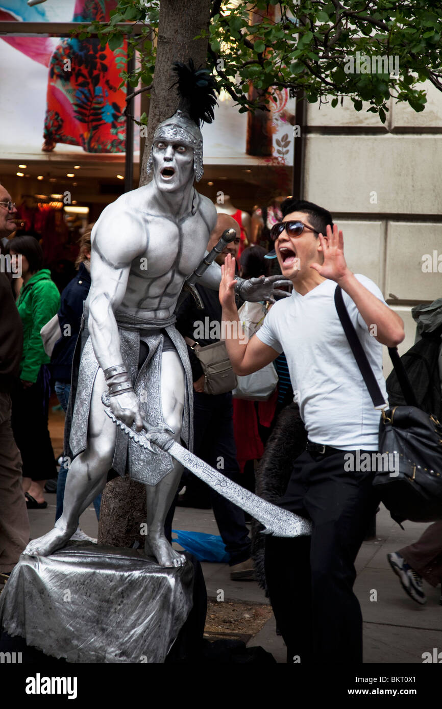 Street performer scherzi con un turista in Covent Garden di Londra. Questa zona è molto popolare per il turismo. Foto Stock