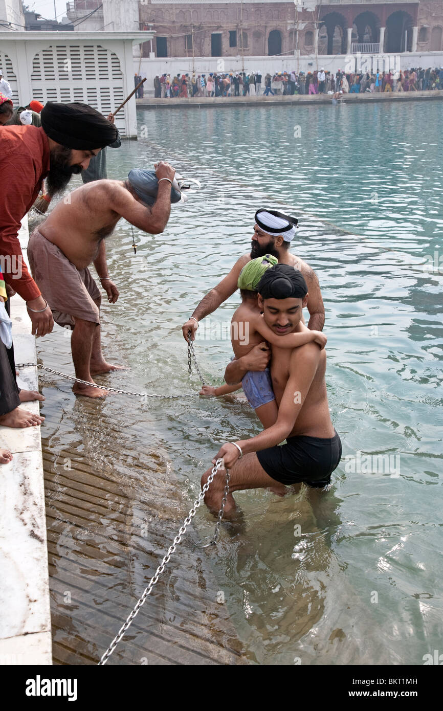 I sikh devoti facendo il bagno rituale nella piscina sacra. Il Tempio Dorato. Amritsar. Il Punjab. India Foto Stock