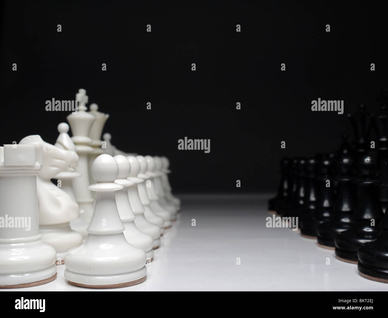 Righe di bianco e nero set di scacchi in piedi faccia a faccia su sfondo nero Foto Stock