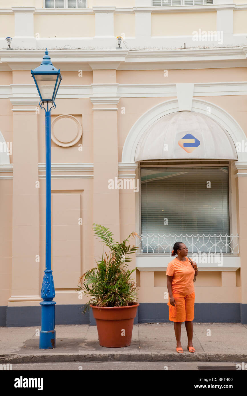 Signora nera in attesa di un autobus a Bridgetown, Barbados, West Indies. Foto Stock