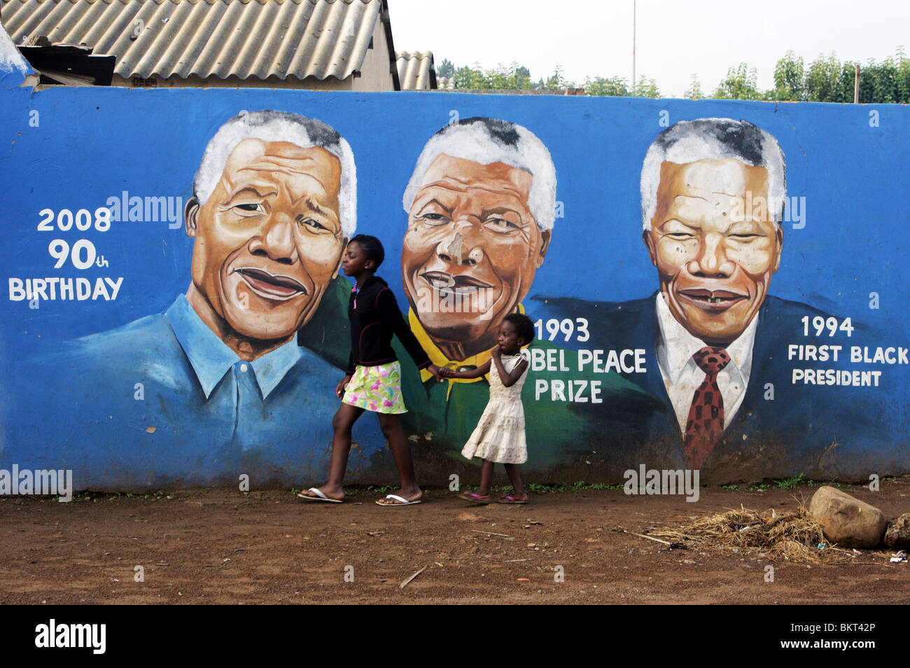 I bambini passando a Nelson Mandela carta murale nelle township Soweto, Johannesburg, Sud Africa Foto Stock