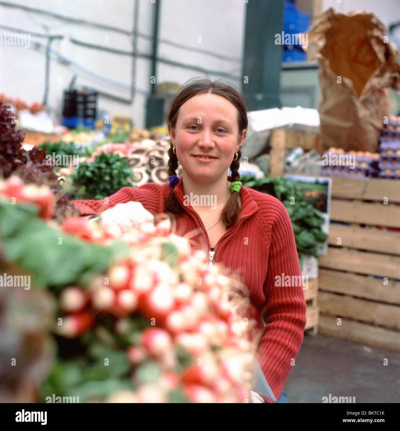 Una giovane commerciante di mercato donna che vende ravanelli su una bancarella di verdure di ravanello a Borough Market, London Bridge, Londra del sud, Regno Unito Gran Bretagna KATHY DEWITT Foto Stock