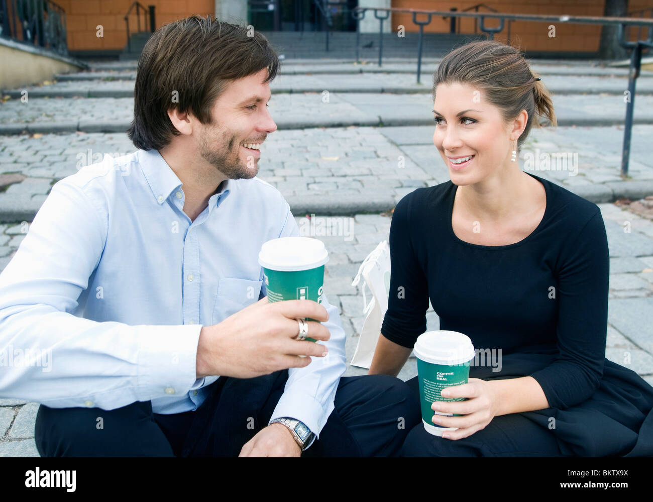 L uomo e la donna seduta sulle scale di bere il caffè Foto Stock