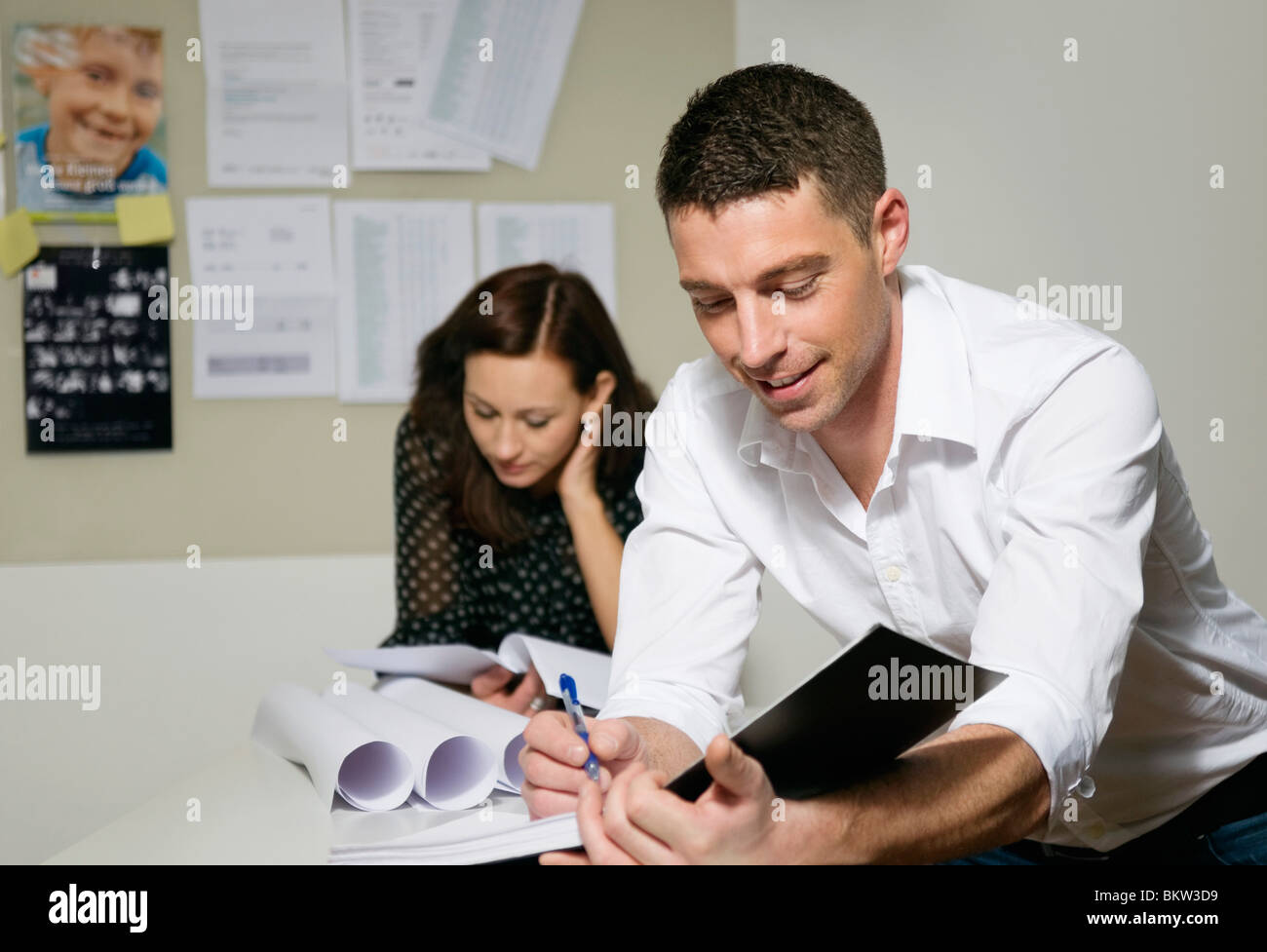 L'uomo prendendo appunti, donna lettura in background Foto Stock