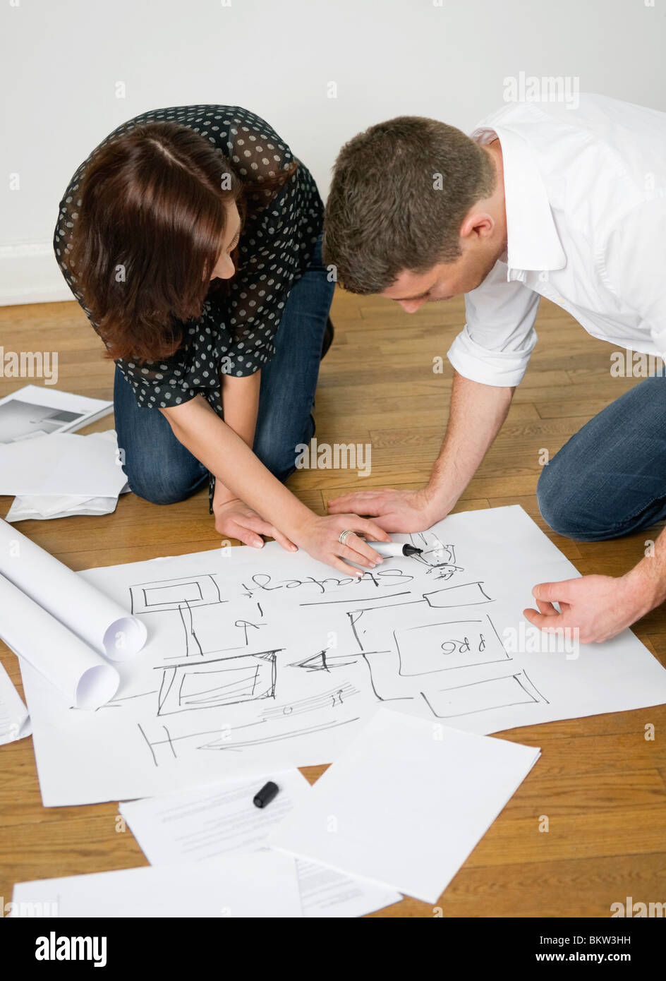 Due persone che guardano blueprint sul pavimento Foto Stock