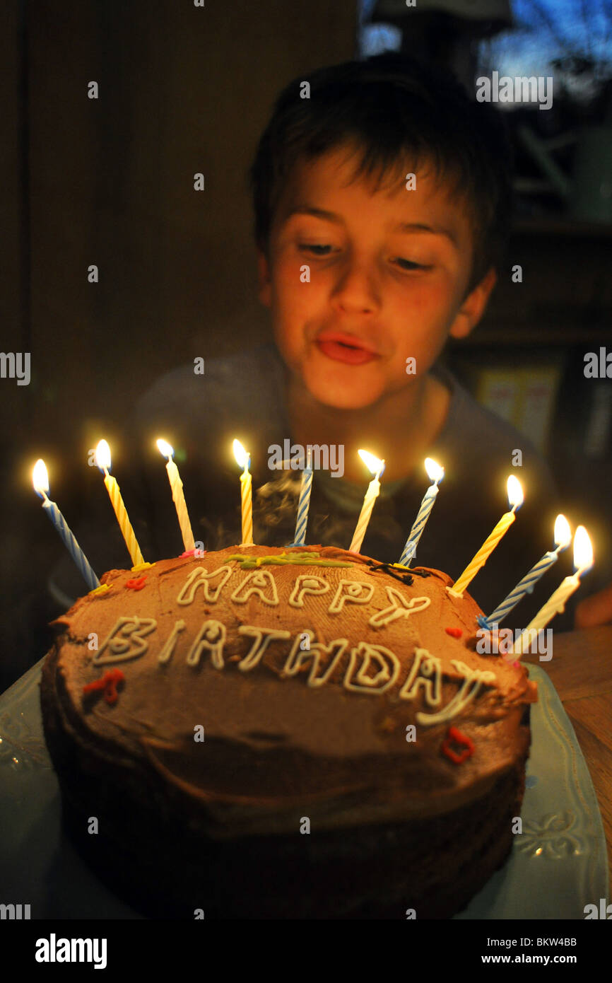 A dieci anni di vecchio ragazzo si brucia le candele sulla sua torta di compleanno Foto Stock