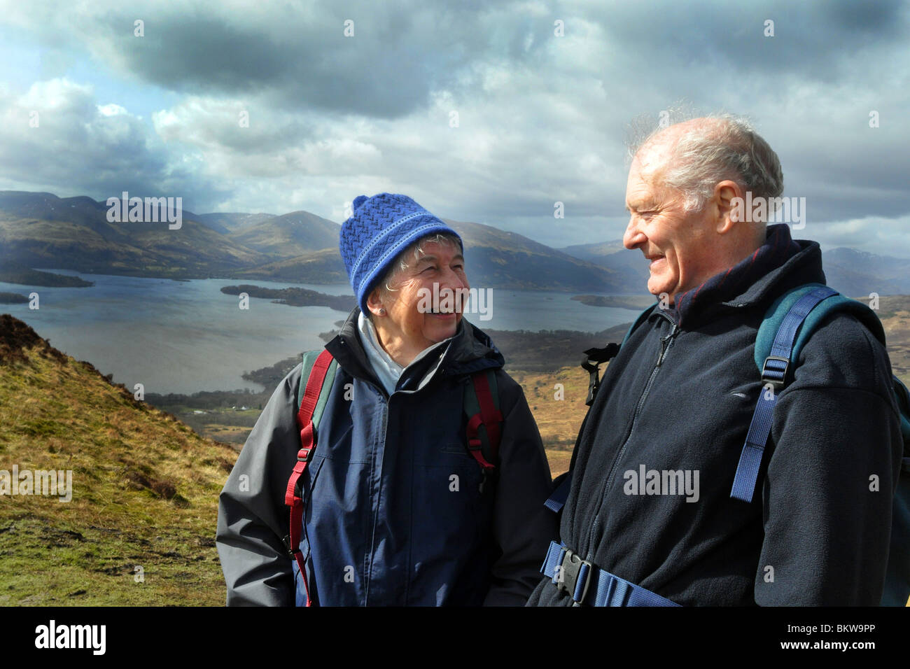 Persone anziane attive andare passeggiate in collina nel Trossachs National Park, Scozia Foto Stock