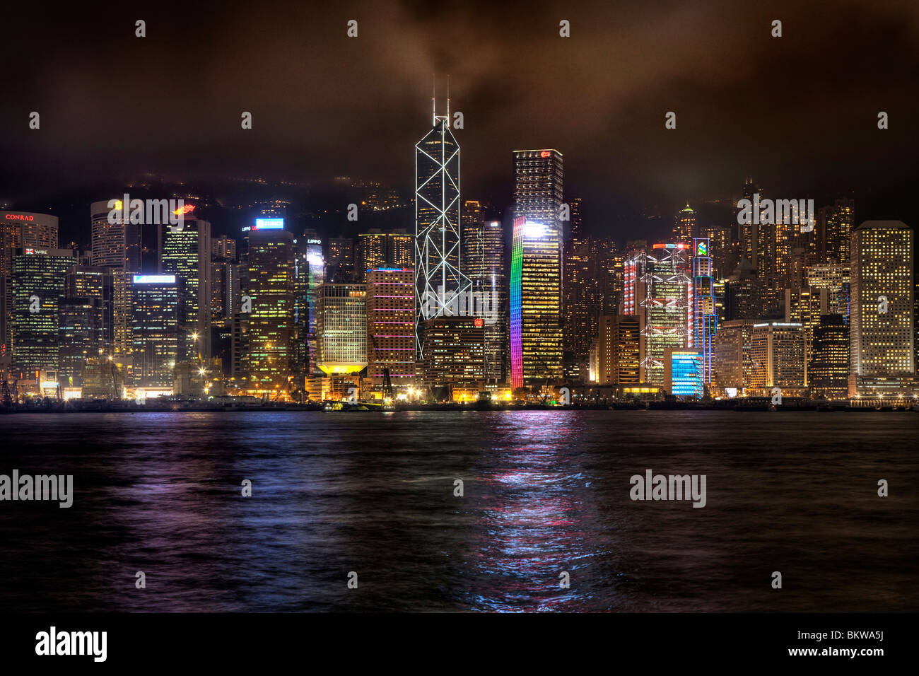 Edifici alti sull isola di Hong Kong city center come visto attraverso il porto da Tsim Sha Tsui in Kowloon Side di notte Foto Stock