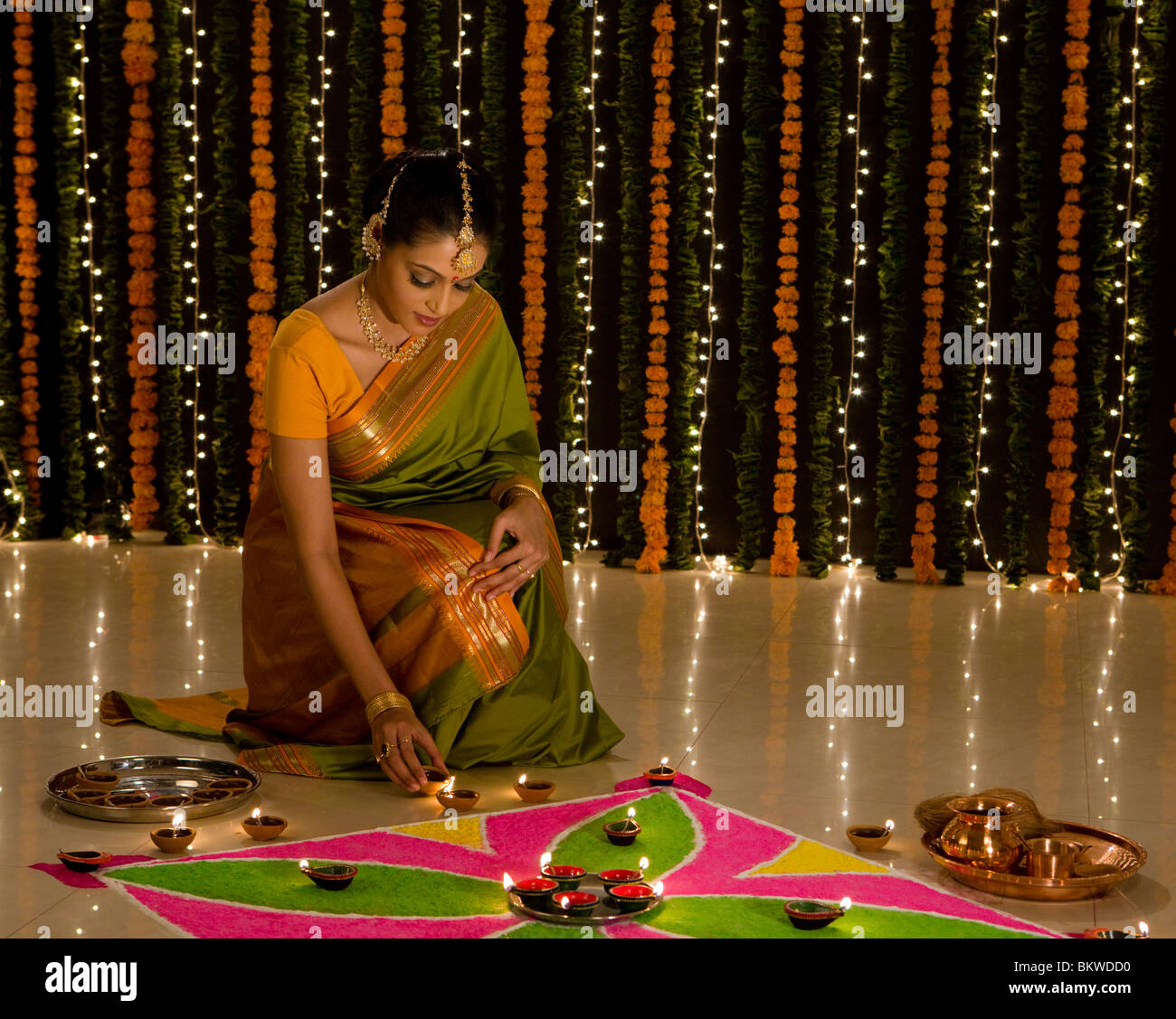 Donna indiana di illuminazione un olio lampada di fronte rangoli Foto Stock