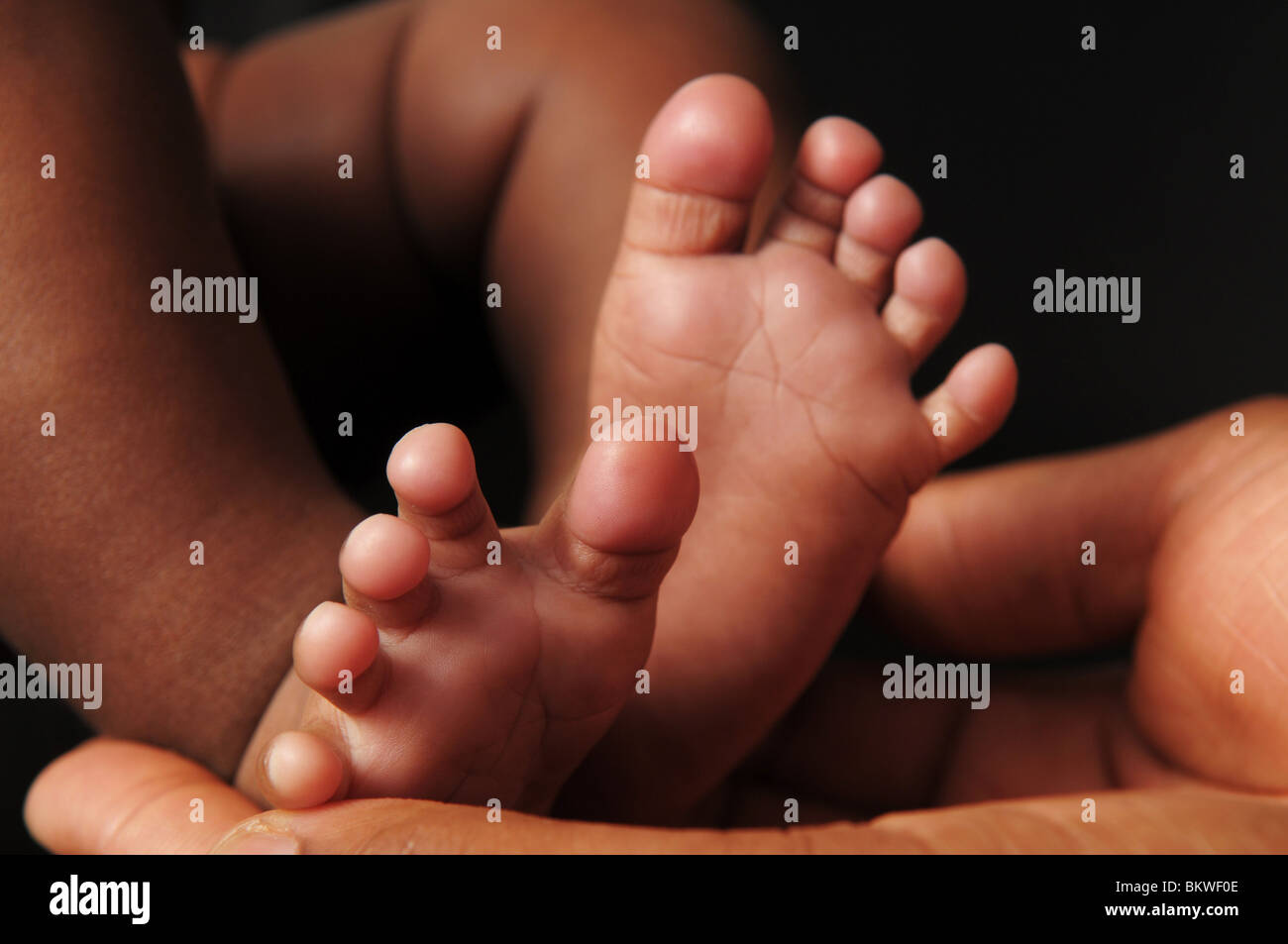Una madre culle i piedi del suo bambino Foto Stock