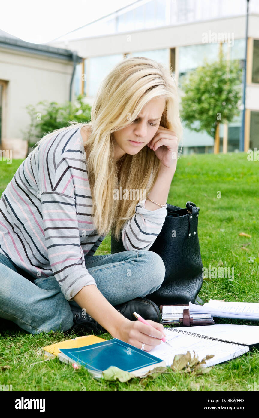 Donna seduta al di fuori la scrittura nel blocco note Foto Stock