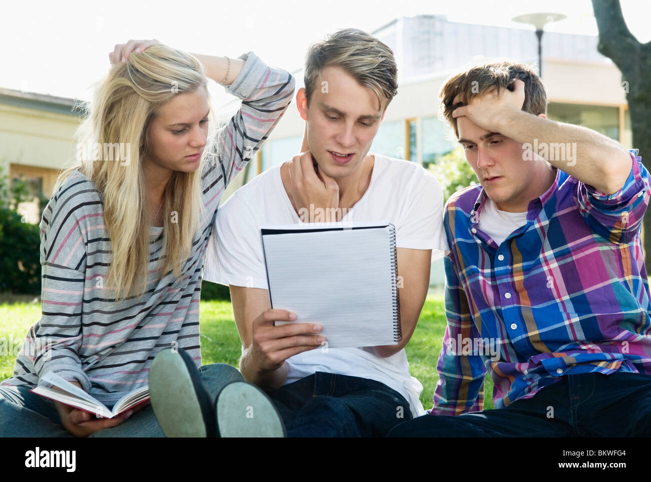 Tre studenti seduti fuori a studiare Foto Stock
