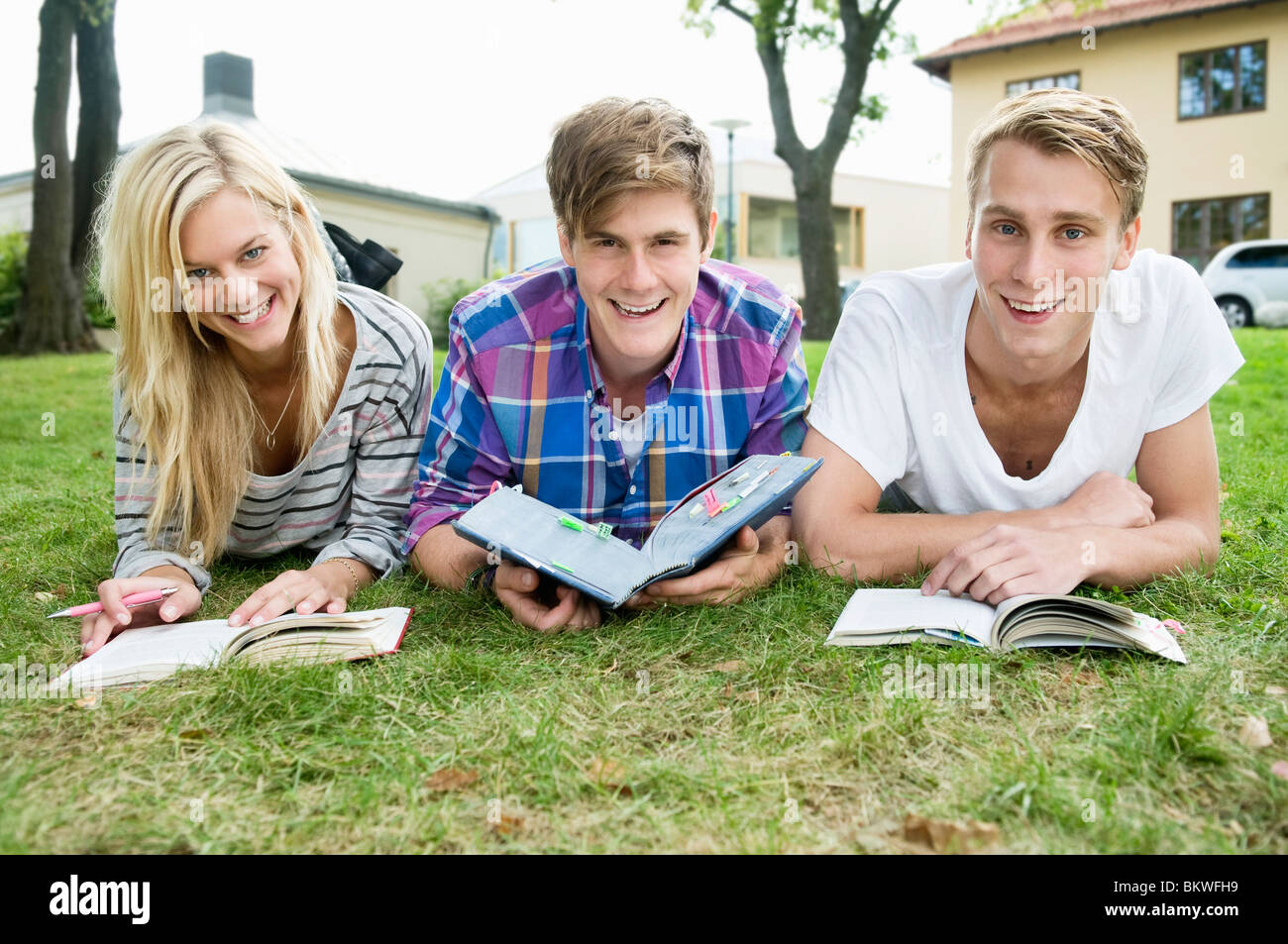 Tre Allievi felici giacente al di fuori lo studio Foto Stock