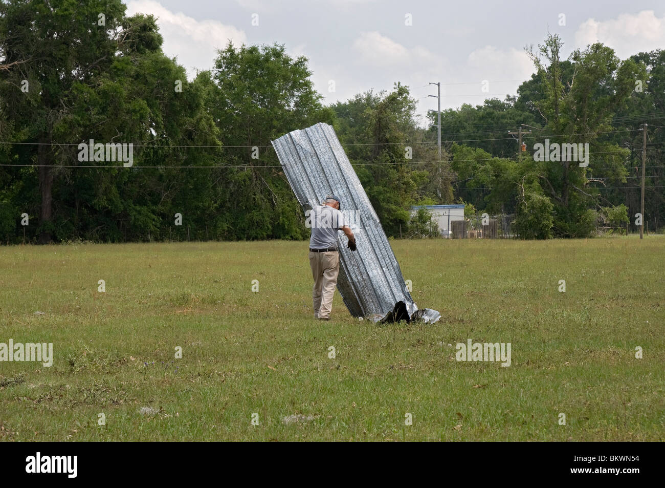 Uomo di parti in movimento di un fienile gettato nella terra di pascolo dopo il tornado toccato durante la tempesta nei pressi di Branford Florida Foto Stock