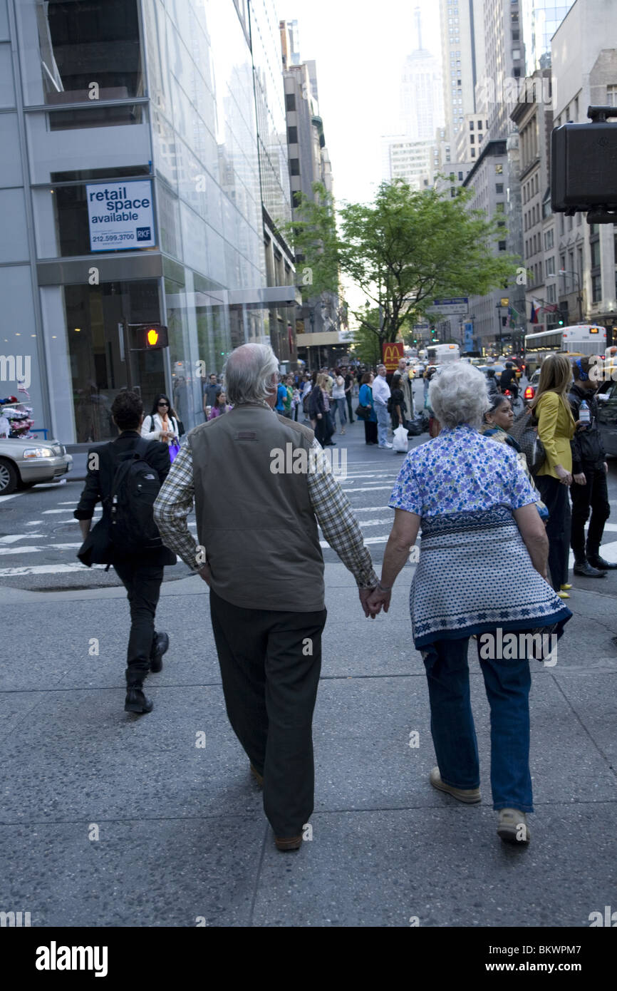 Coppia di anziani passeggiate mano nella mano lungo la Quinta Avenue in New York City. Foto Stock