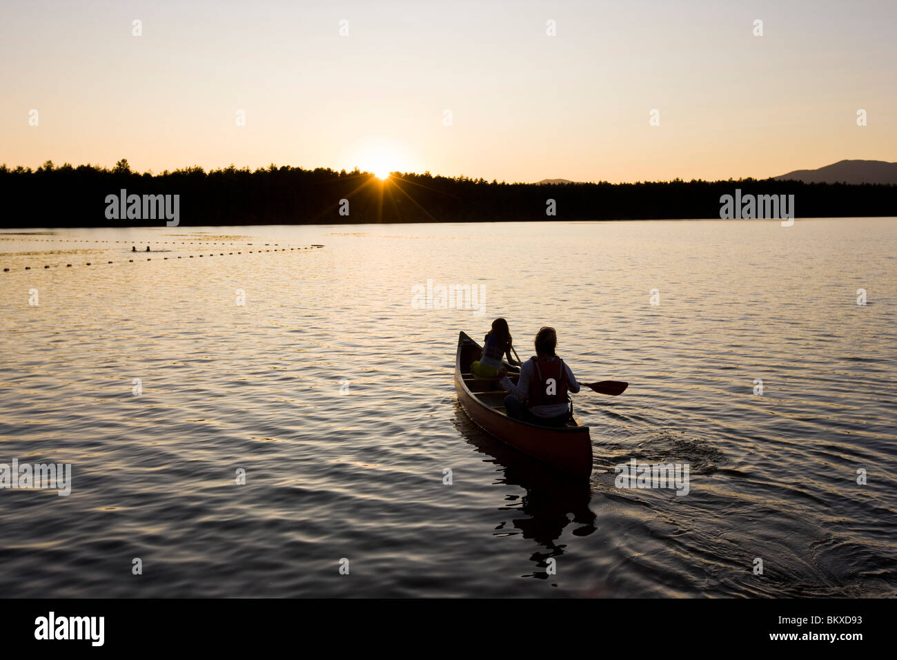 Una donna e di sua figlia canoa al tramonto al Lago Bianco del parco statale in Tamworth, New Hampshire. Foto Stock