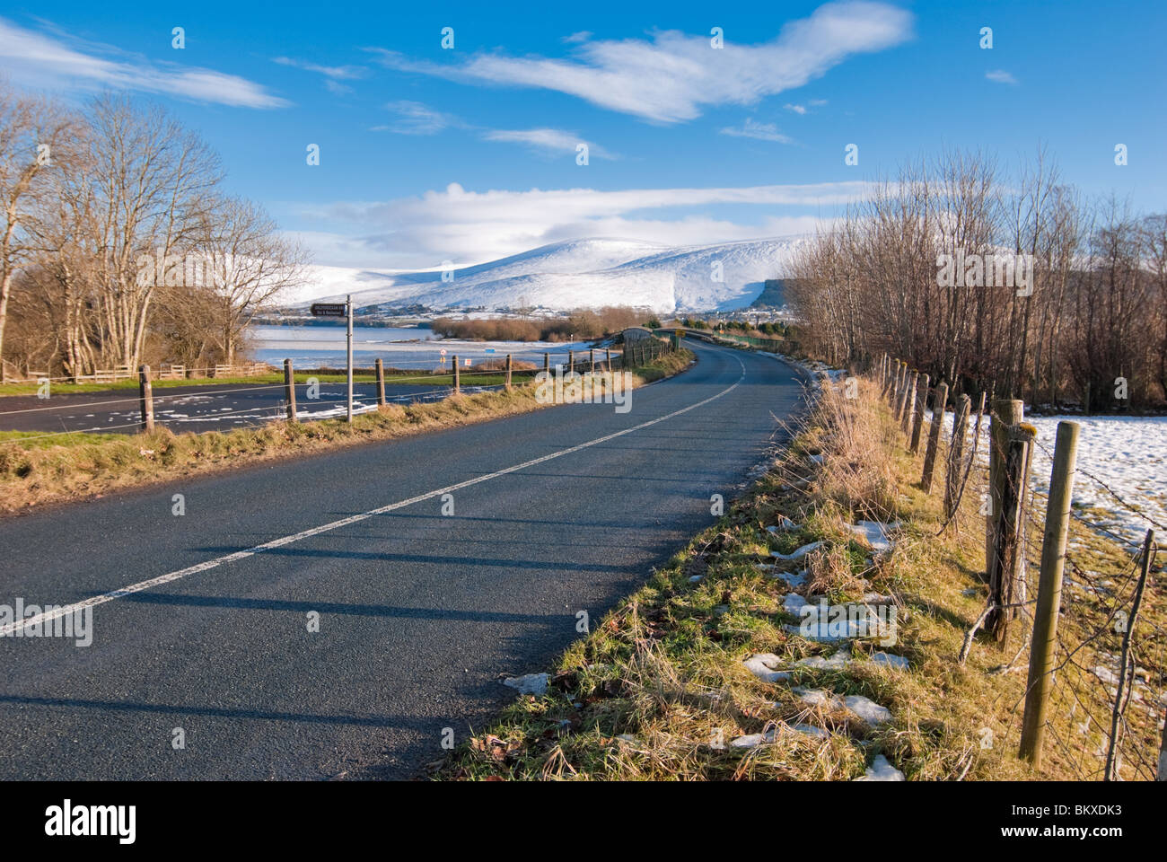 Un solitario strada conduce attraverso il ghiaccio coperto Poulaphouca serbatoio e sul verso la Contea di Wicklow Mountains. Foto Stock