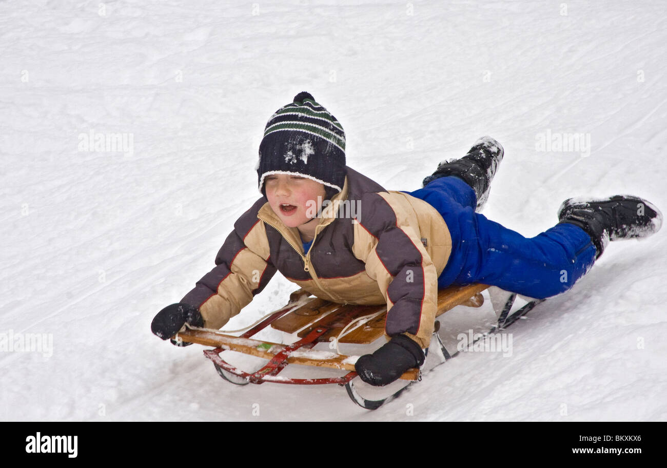 Bambini sled giù breve pendio in inverno, South Lake Tahoe. Qui, un ragazzo arriva giù per la collina con un sguardo determinato sul suo volto Foto Stock
