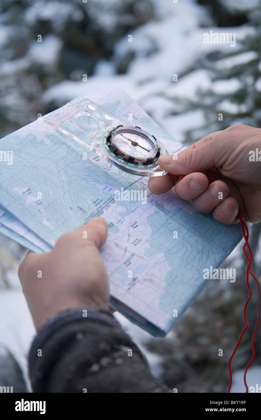 Un maschio di escursionista controlla la sua posizione con una bussola e cartina topografica. Foto Stock