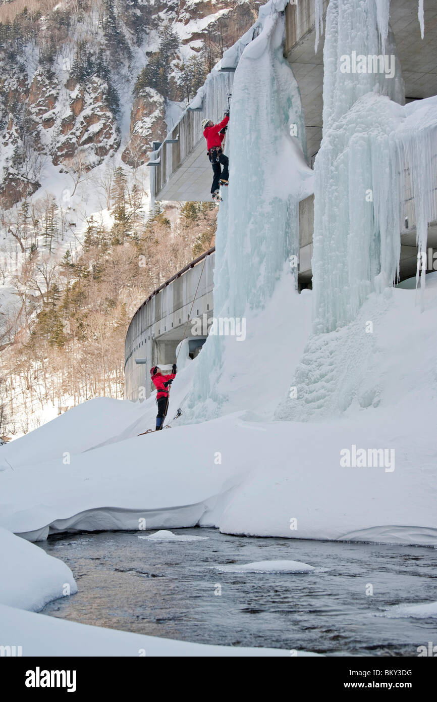 Un uomo è belayed durante la salita di un pilastro di ghiaccio su una autostrada in Sounkyo Gorge, Daisetsuzan National Park, Hokkaido, Giappone. Foto Stock