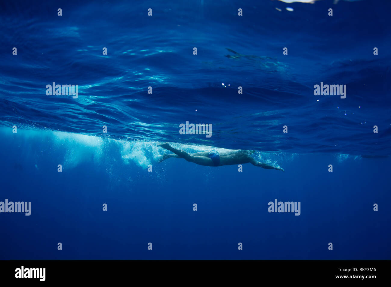 Vista subacquea di un nuotatore che gode di una rilassante nuotata in acque tropicali al di fuori dell'Isola di Mana, Fiji. Foto Stock