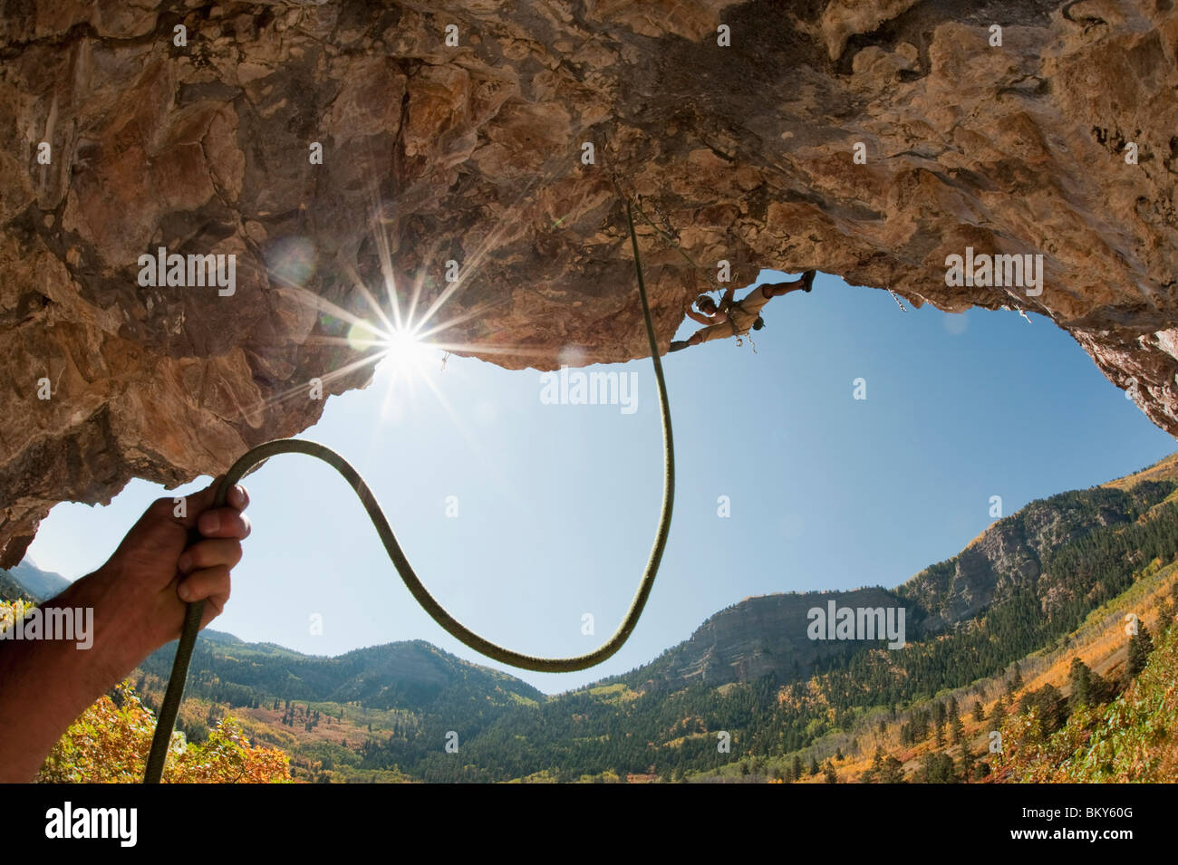 Un belayers mano che tiene la corda che conduce a un uomo di arrampicata su roccia presso il Golf a parete, San Juan National Forest, Durango, Colorado. Foto Stock